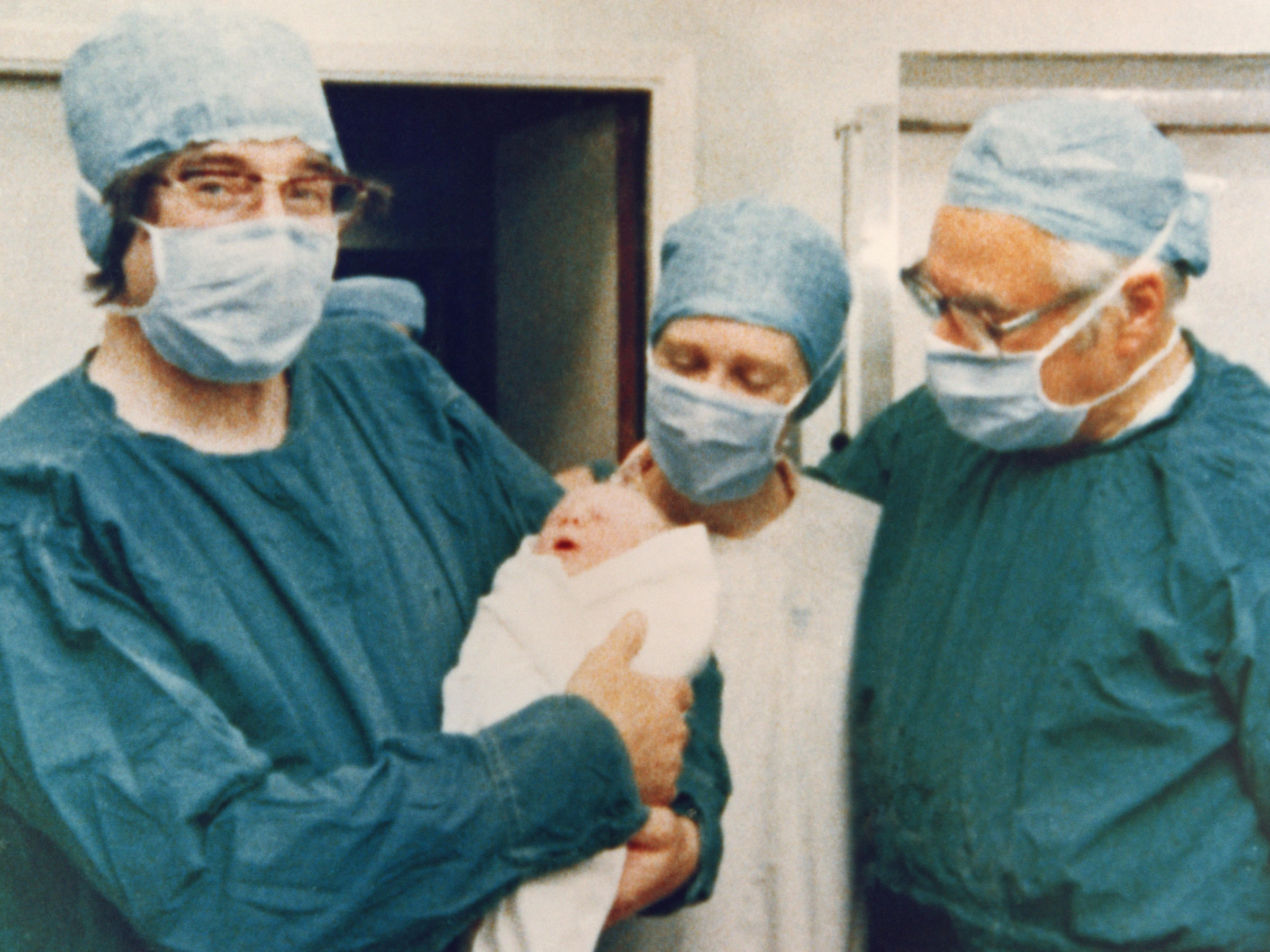 Dr. Robert Edwards holds the world's first "test-tube baby," Louise Brown, on July 25, 1978. A midwife stands in the center, with gynecologist Patrick Steptoe on the right.